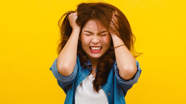 1920-asian-female-with-negative-expression-over-yellow-background.jpg