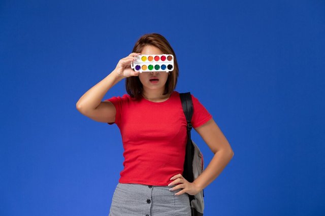 front-view-female-student-red-shirt-with-backpack-holding-paints-drawing-blue-wall_140725-38423.jpg