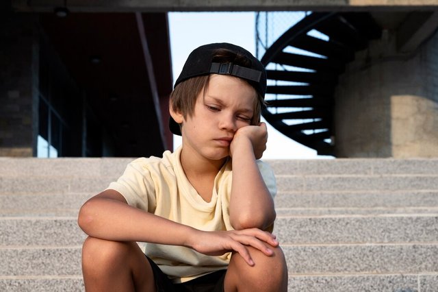 front-view-sad-boy-sitting-stairs_23-2149599380.jpg