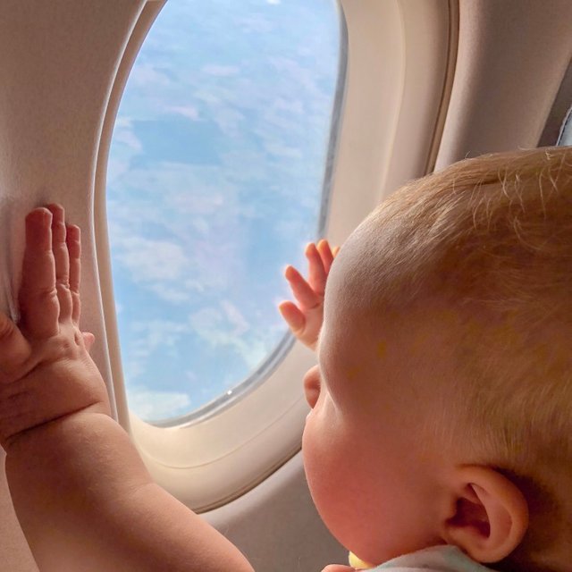 little-baby-is-looking-through-the-window-in-plane-clouds-in-the-sky-are-visible-in-the-illuminator_t20_roabgZ.jpg