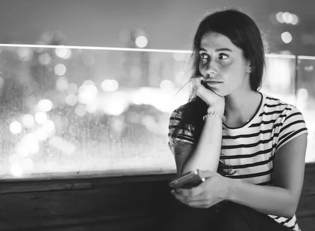 unhappy-young-woman-holding-smartphone-evening-cityscape_53876-20474.webp