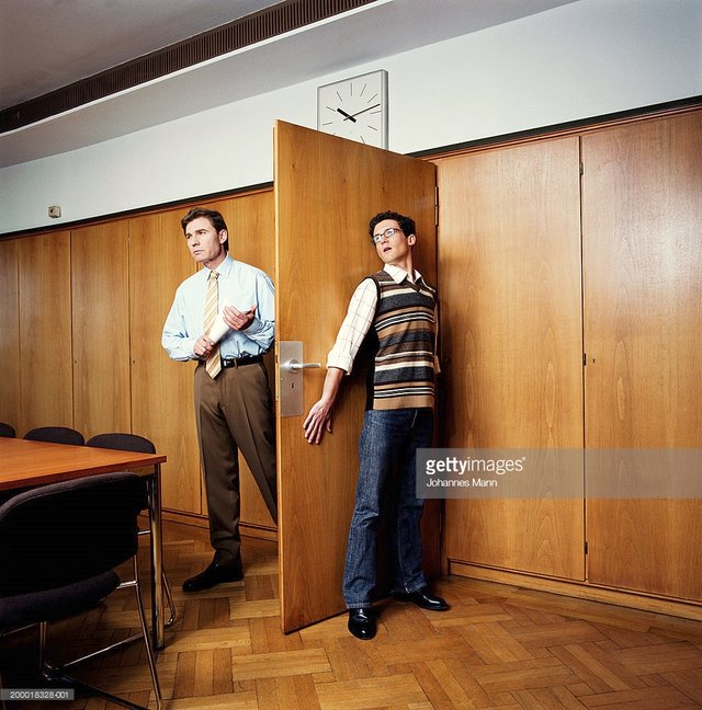 businessman-entering-room-young-man-hiding-behind-door-picture-id200018328-001.jpeg