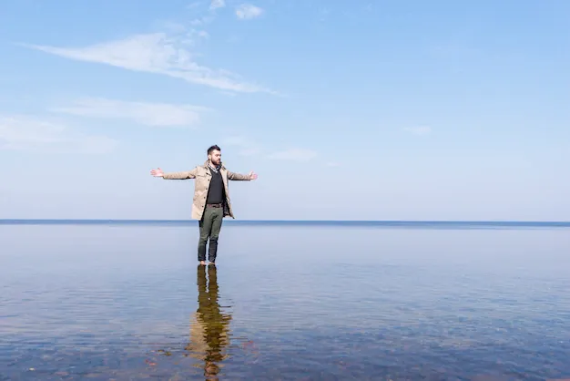 lone-young-man-outstretching-his-hand-standing-shallow-sea-water_23-2148148622.webp