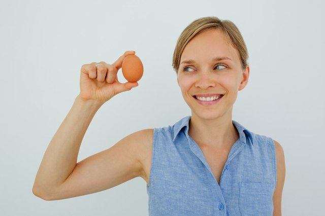 smiling-woman-holding-egg-with-two-fingers_1262-5699.jpg