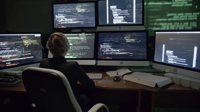 videoblocks-rear-view-of-female-hacker-sitting-in-the-dark-office-in-front-of-six-monitors-with-data-and-typing-computer-commands_sds581xm_thumbnail-full01.png