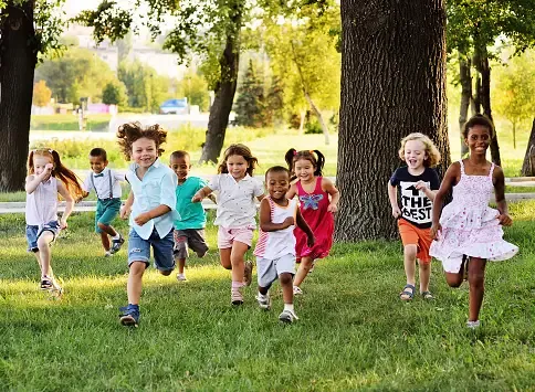 a-group-of-preschoolers-running-on-the-grass-in-the-park.webp