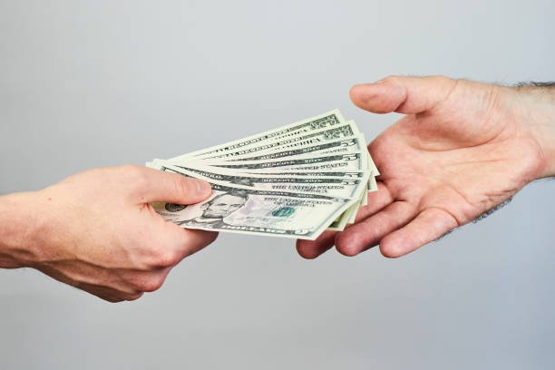 business-closeup-of-two-hands-exchanging-dollars-on-grey-background.jpg