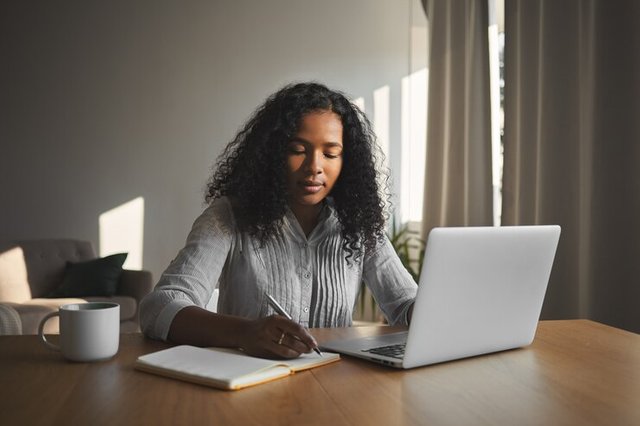 beautiful-mixed-race-student-girl-with-voluminous-hairdo-working-home-assignment-her-room-sitting-wooden-desk-using-laptop-writing-down-copybook-people-technology-education_343059-1791.jpg