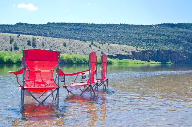 Red folding chairs on the green river.JPG