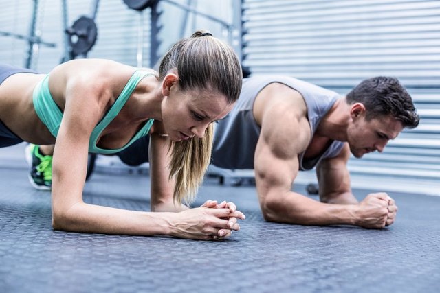 Side view of a muscular couple doing planking exercises.jpeg