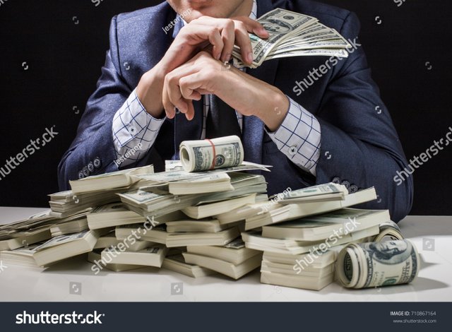 stock-photo-man-holding-money-in-hand-at-black-background-man-receive-a-lot-money-from-trading-business-710867164.jpg