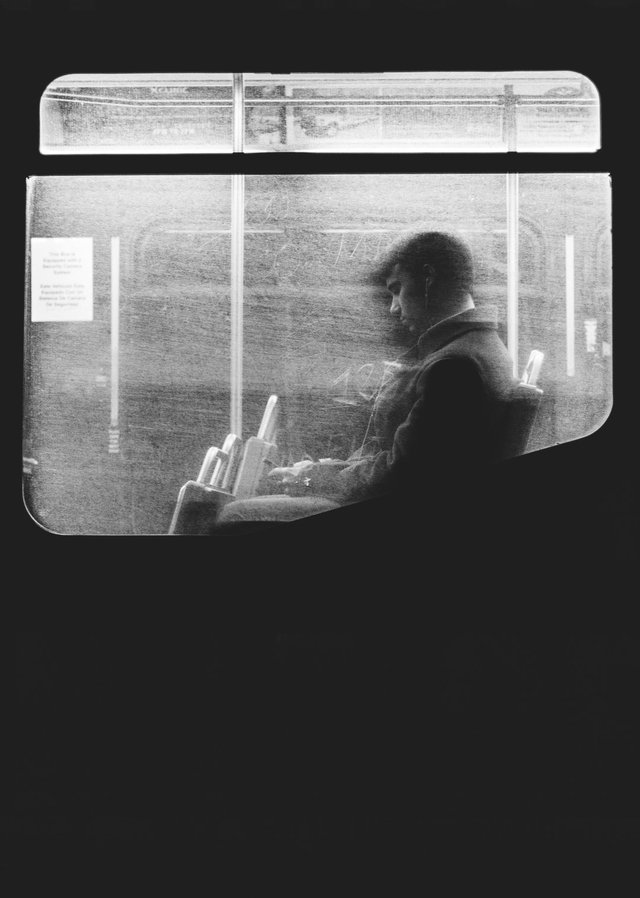 black_and_white_shot_of_man_sitting_on_night_bus_through_dirty_window_in_boston.jpg