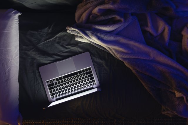 laptop-with-glowing-screen-bed-night-top-view-copy-space.jpg