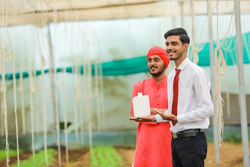 young-indian-agronomist-and-farmer-showing-bottle-at-greenhouse (2).jpg