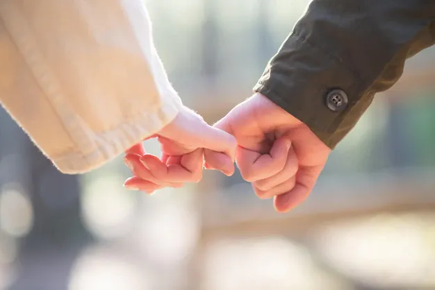 close-up-couple-holding-hands-caucasian-couple-holding-each-others-little-fingers-love-affection-relationship-concept_74855-23536.webp