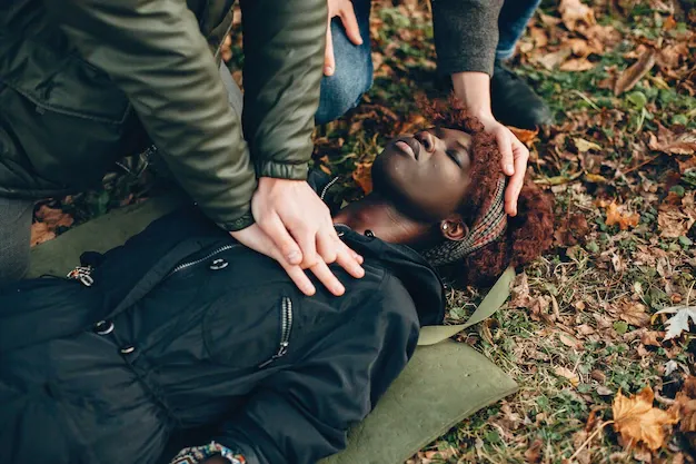 guys-help-woman-african-girl-is-lying-unconscious-providing-first-aid-park_1157-40386.webp