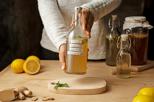 front-view-hands-holding-kombucha-bottle_23-2149704019.jpg