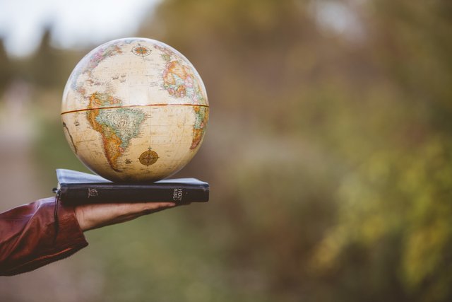 closeup-shot-person-holding-bible-with-desk-globe-top.jpg