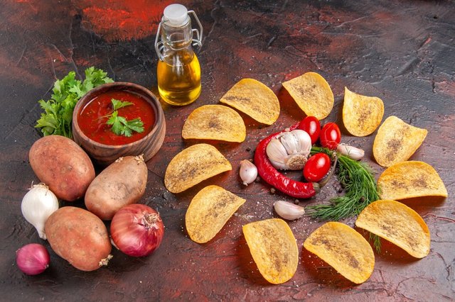 side-view-homemade-delicious-crispy-chips-red-pepper-garlic-green-tomatoes-ketchup-potatoes-onion-oil-bottle-dark-table_140725-140989.jpg