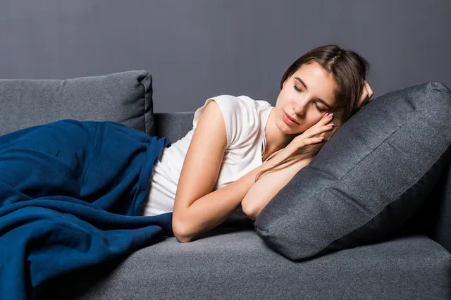young-girl-sleeping-sofa-covered-with-blue-coverlet-gray-background_231208-5164.webp