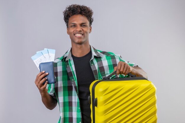 young-african-american-traveler-man-standing-with-suitcase-holding-air-tickets-smiling-cheerfully-positive-happy-white-background_141793-22262.jpg