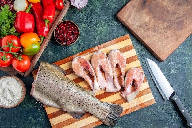 top-view-raw-fish-slices-cutting-board-vegetables-wood-serving-board-knife-kitchen-table_179666-46551.jpg