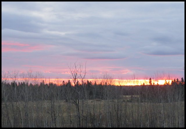 horizon looks like it is on fire with the setting sun pink highlights the clouds.JPG