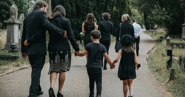 11599-family-walking-away-after-funeral-in-cemetery.webp