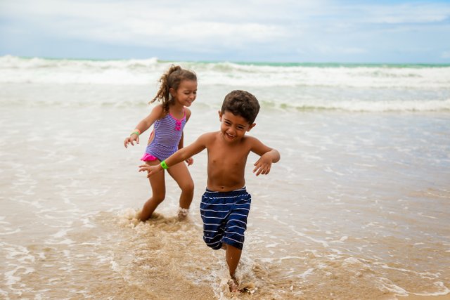 photo-of-children-smiling-while-running-on-seashore-3188574.jpg