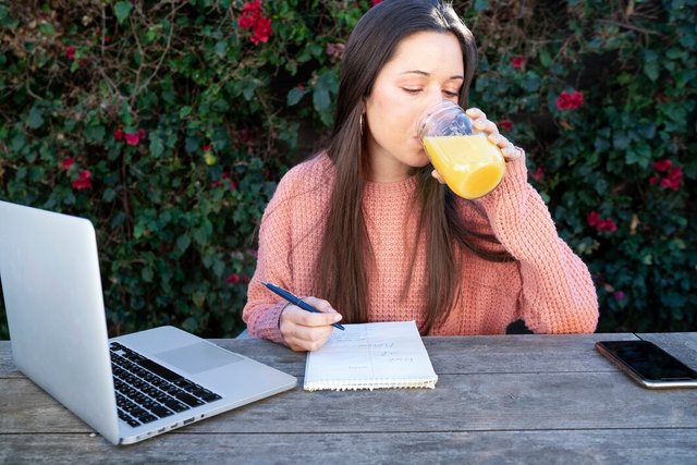 young-woman-taking-notes-outdoors-while-using-laptop-drinking-orange-juice_23-2149342438.jpg