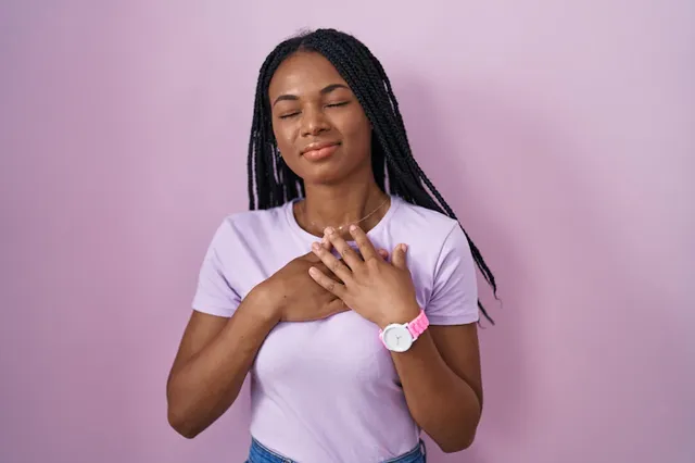 african-american-woman-with-braids-standing-pink-background-smiling-with-hands-chest-with-closed-eyes-grateful-gesture-face-health-concept_839833-2207.webp