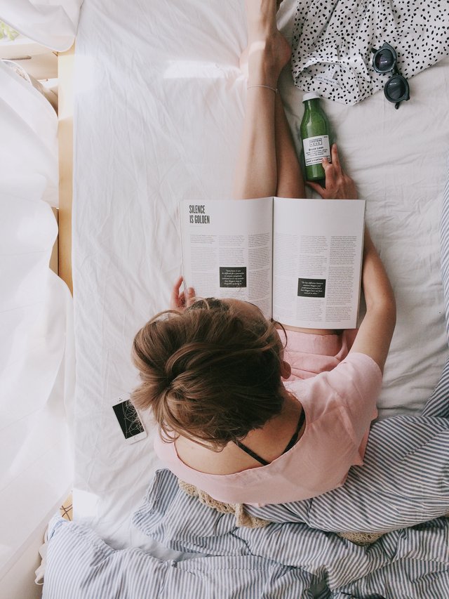 woman-in-pink-dress-sitting-on-bed-while-reading-698158.jpg