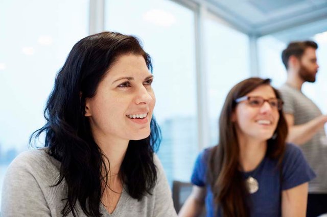 two-businesswomen-women-seated-at-a-desk-talking-a-NH4JKEV.jpg