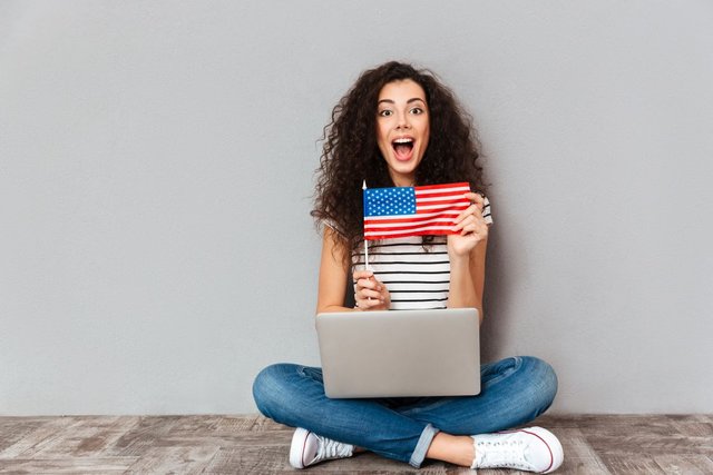 gorgeous-female-with-beautiful-smile-sitting-lotus-pose-with-silver-computer-legs-demonstrating-american-flag-grey-wall1.jpg