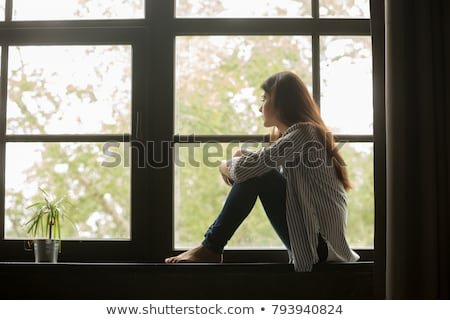 thoughtful-girl-sitting-on-sill-450w-793940824.jpg