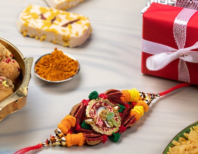 Firefly Rakhi on a table with Indian sweets and gifts 42260.jpg