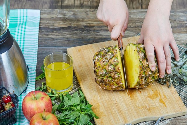woman-cutting-fresh-pineapple-wooden-cutting-board-apples-greens-glass-juice_114579-56171.jpg