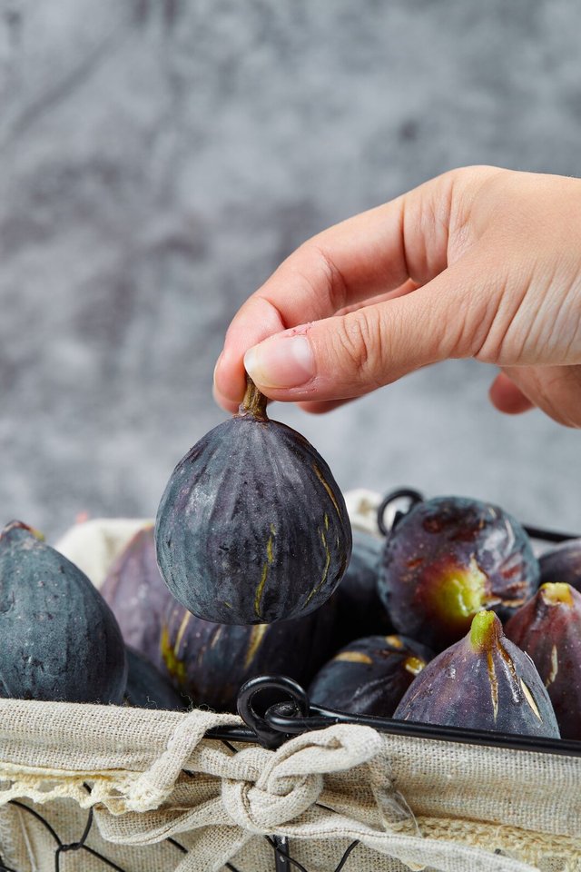 hand-holding-fig-from-basket-marble_114579-29532.jpg