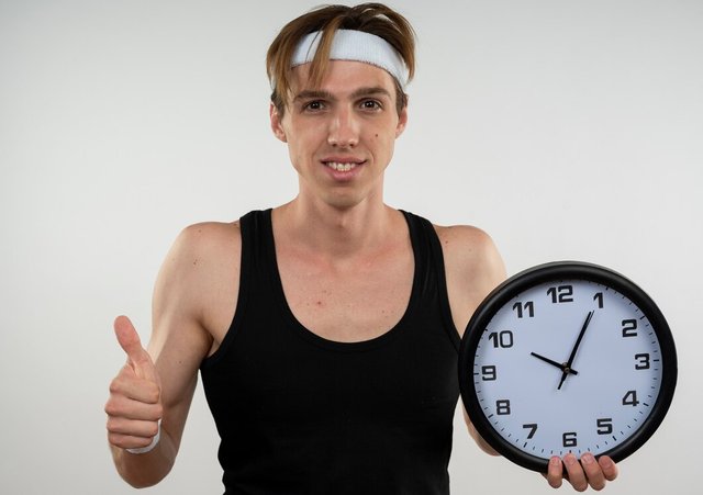 smiling-young-sporty-guy-wearing-headband-wristband-holding-wall-clock-showing-thumb-up-isolated-white_141793-85785.jpg