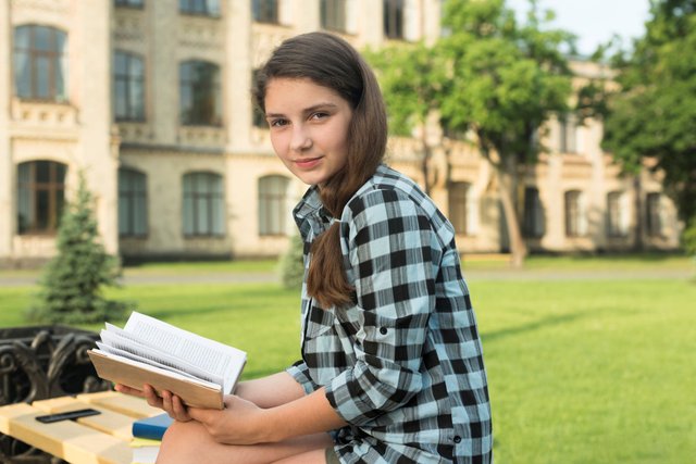 side-view-medium-shot-teenage-girl-holding-open-book 1.jpg