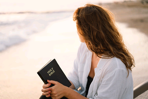 christian-woman-holds-bible-in-her-hands-reading-the-holy-bible-on-the-sea-during-beautiful.jpg