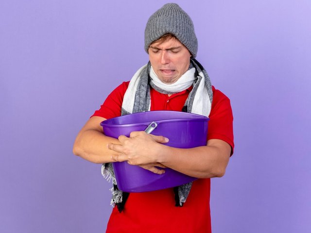 frowning-young-handsome-blonde-ill-man-wearing-winter-hat-scarf-holding-plastic-bucket-with-closed-eyes-having-nausea-isolated-purple-wall-with-copy-space_141793-80094.jpg