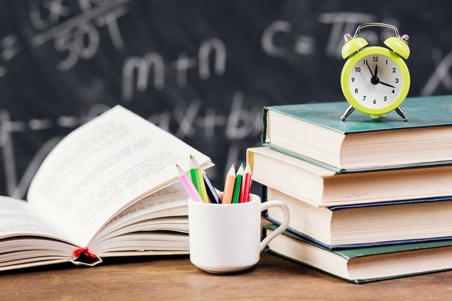 clock-on-top-of-textbooks-at-teacher-desk_23-2148199985.jpg