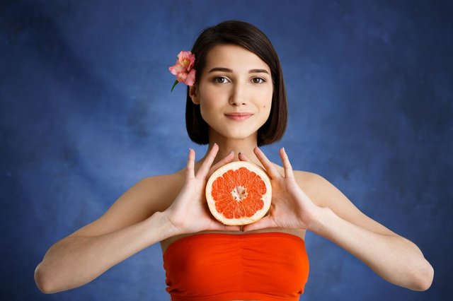 close-up-portrait-tender-young-woman-holding-cut-orange-blue-wall_176420-2778.jpg