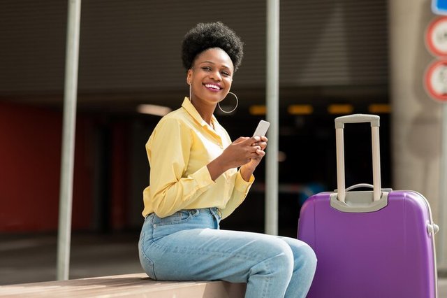 black-woman-tourist-using-smartphone-sitting-with-travel-suitcase-outdoor_116547-53547.jpg