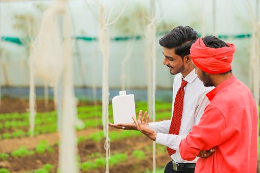 young-indian-agronomist-and-farmer-showing-bottle-at-greenhouse (1).jpg