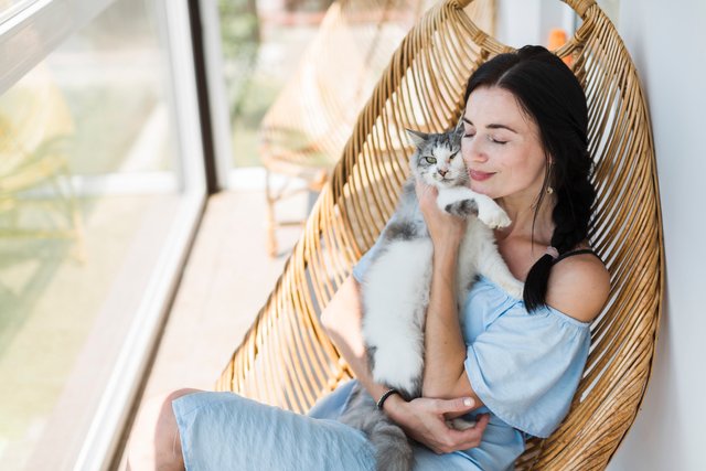 young-woman-sitting-on-chair-at-patio-loving-her-pet-cat.jpg