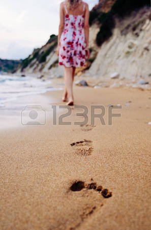 77821002-beauty-young-woman-in-stylish-dress-walking-barefoot-by-the-beach-leaving-footprints-in-sand-at-suns.jpg