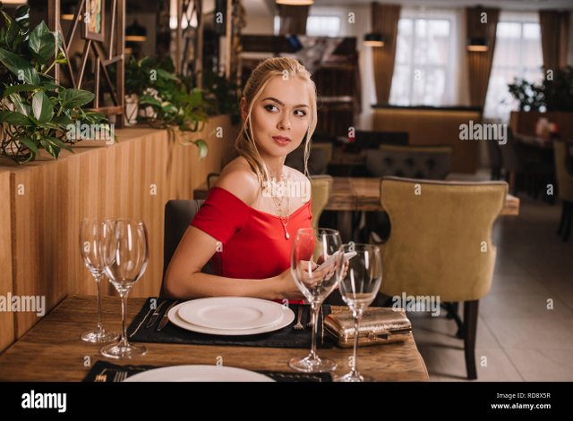 attractive-woman-in-red-dress-sitting-in-restaurant-RD8X5R.jpg