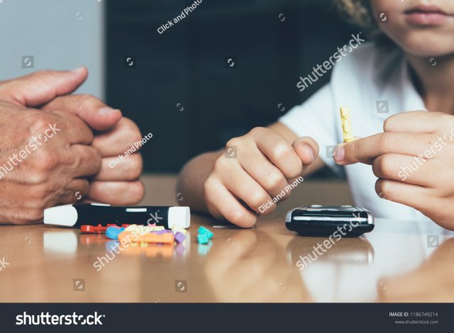 stock-photo-close-up-of-a-hand-of-a-young-diabetic-patient-is-holding-a-lancing-needle-on-a-doctor-desk-in-his-1186749214.jpg